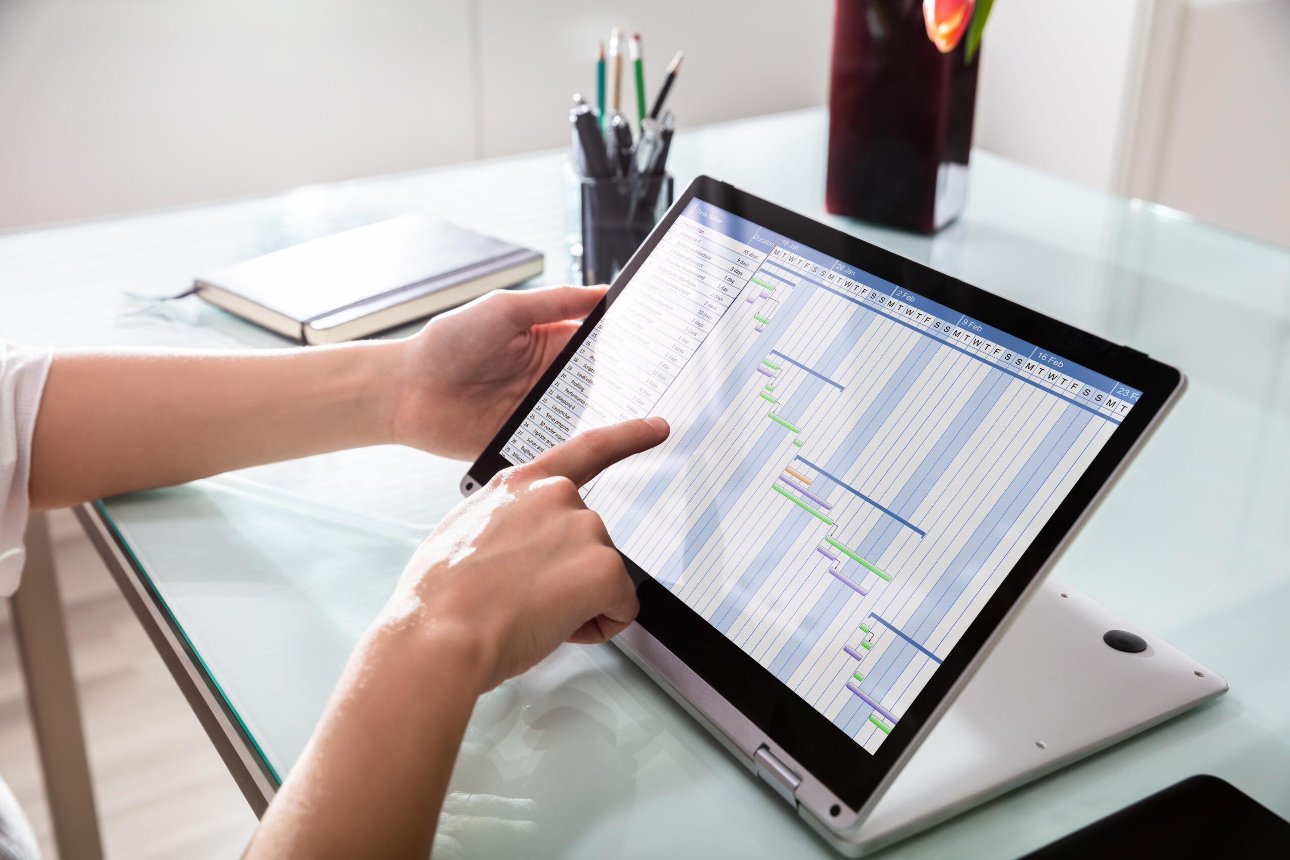Person bearbeitet digitale Fahrtenbuch-Vorlage auf Tablet im Büro